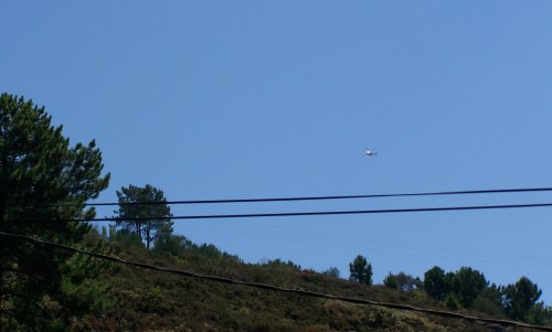 Sobre os cabos do tendido eléctrico e telefónico, apréciase o helicóptero da Policía Nacional, rastrexando o monte na procura dalgún indicio sobre a desaparición de Sonia Iglesias